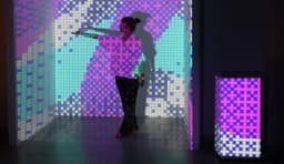 A performer moving in front of a projected MOTIFLOW pattern, with an LED column glowing beside them