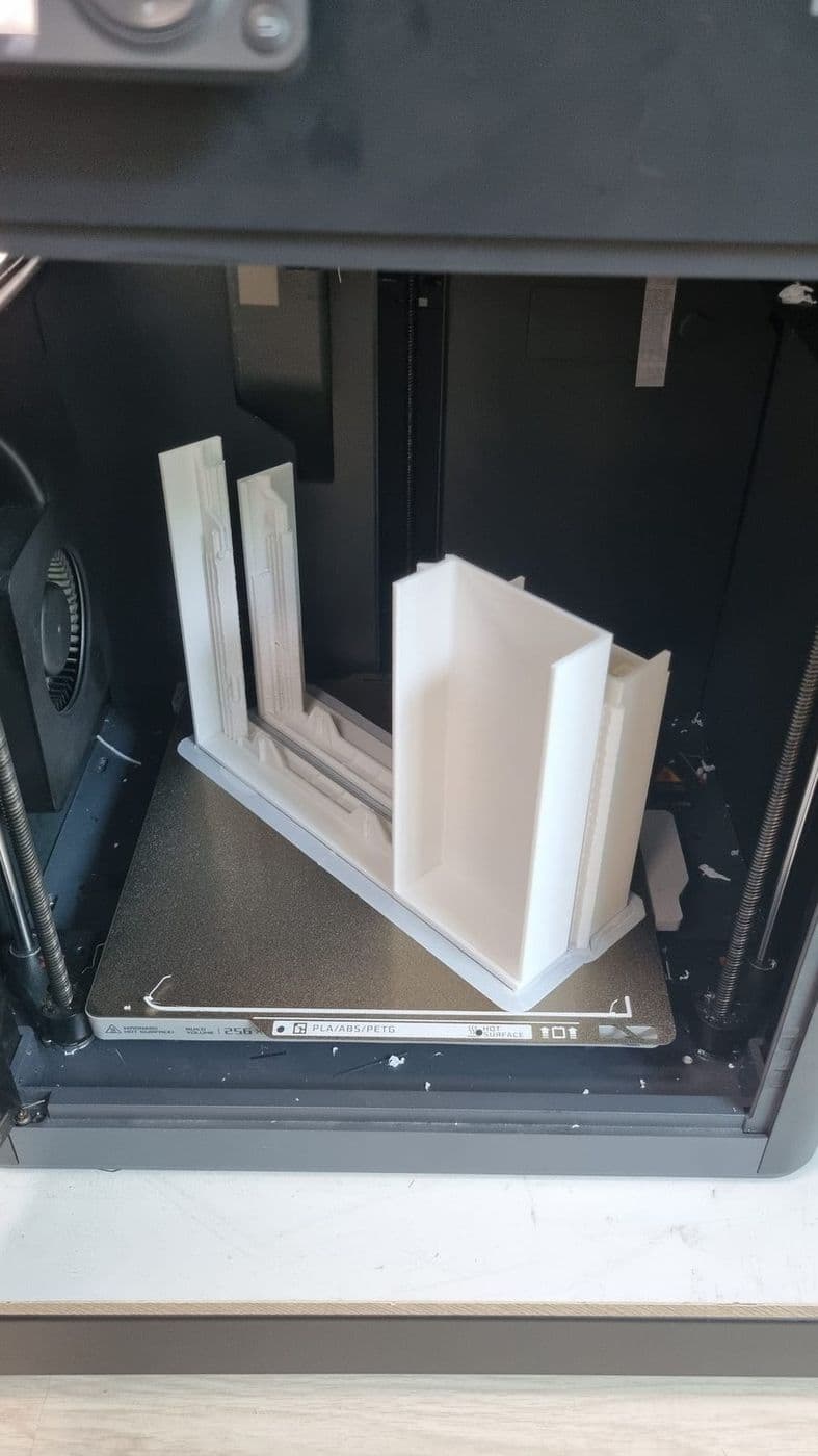 The case printing on a Bambu P1S: the white frame halves standing on the bed
