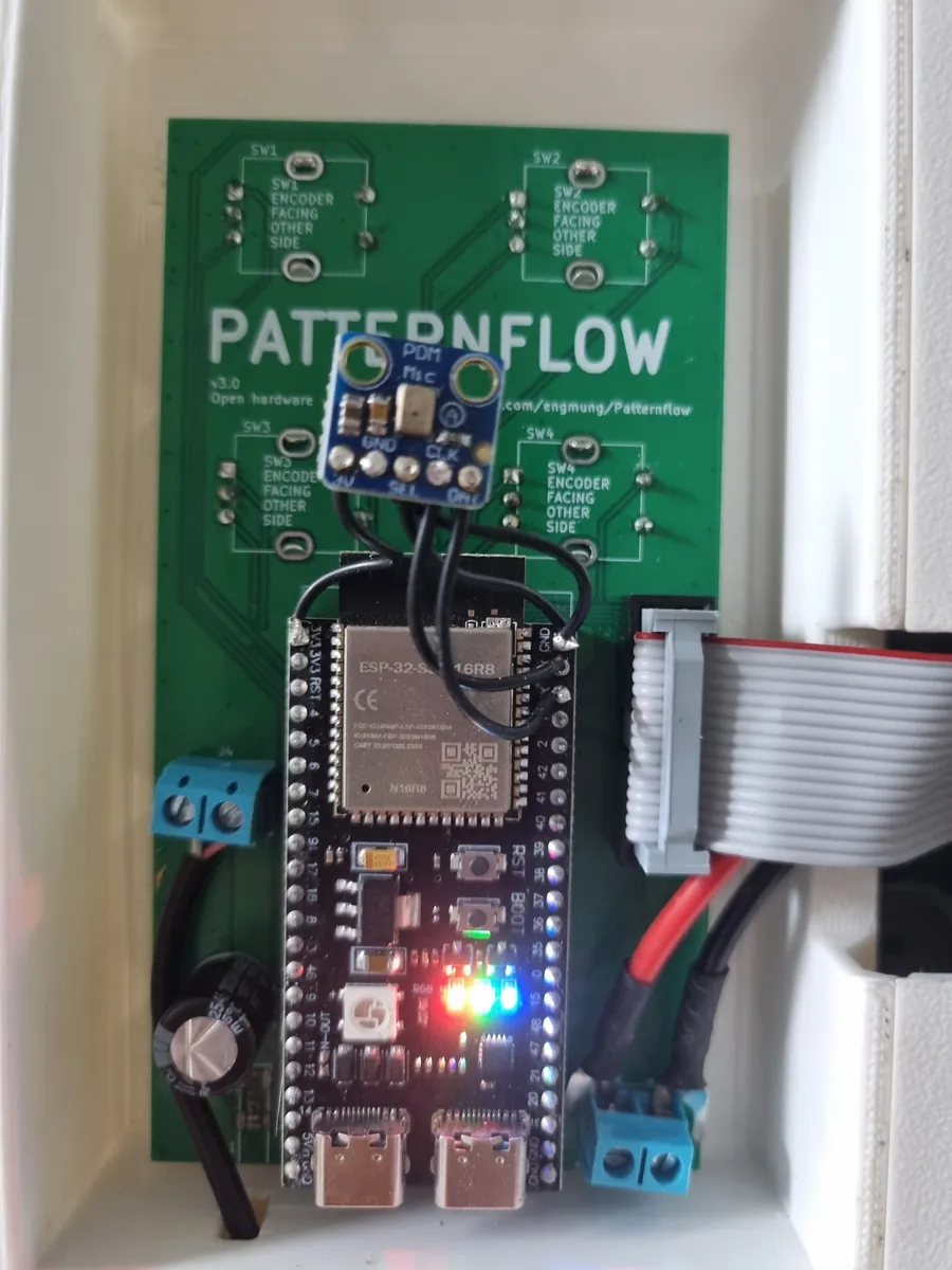 The back of a Patternflow board in its case: the ESP32 module seated in its sockets, the microphone breakout above it on five short leads, and the module's two USB-C ports at the bottom, both empty.